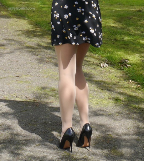 Clothed woman Maria dangles stiletto heels from hose covered feet in a park 54160351