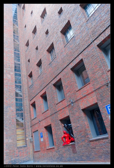 Fetish models pose in latex attire while in a window opening 96222359