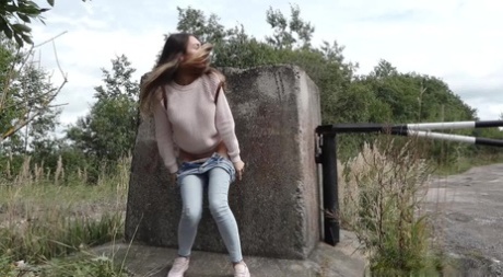 Clothed girl Sasha squats for a piss behind a concrete block on a path 96634674