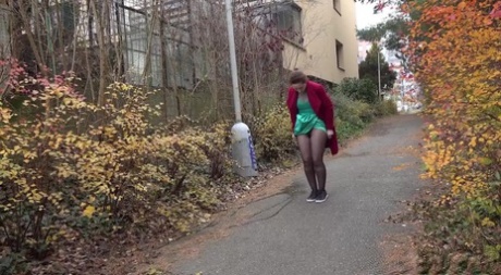 Caucasian female Lora takes a piss while walking on a pathway in the city 95116754